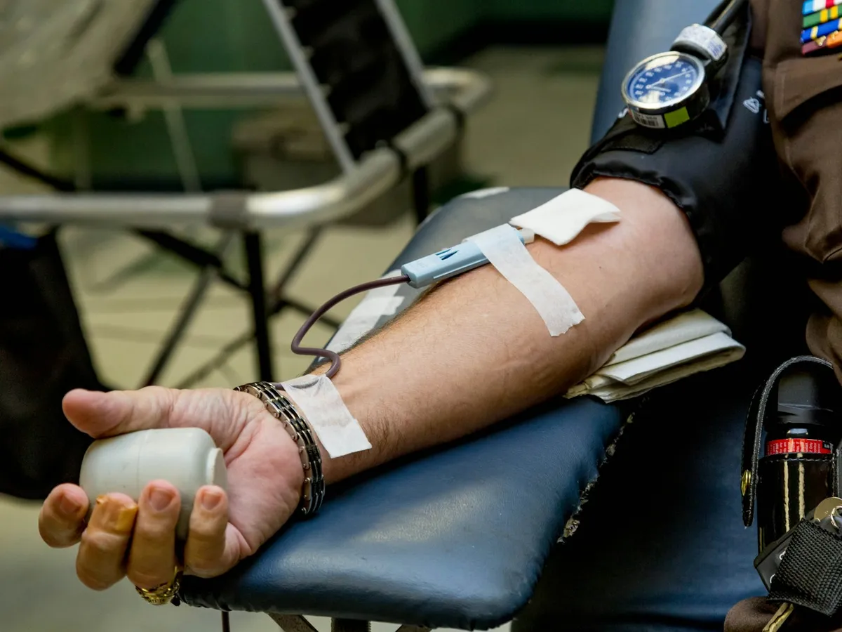 A donor resting during a blood donation, arm bandaged and holding a grip ball