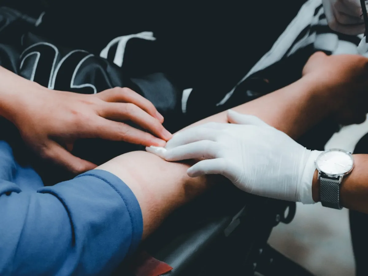 Medical staff attending to a donor's arm during a donation